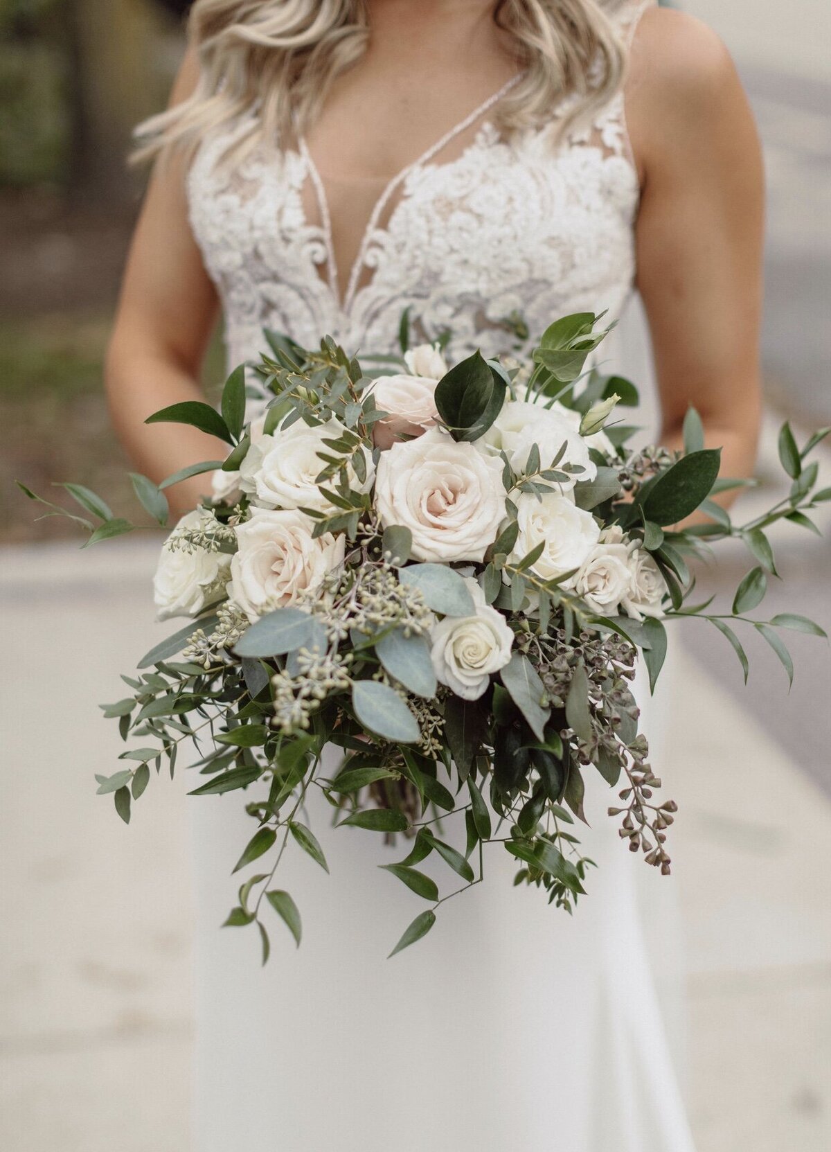 Bride holding bouquet with white flowers and greenery