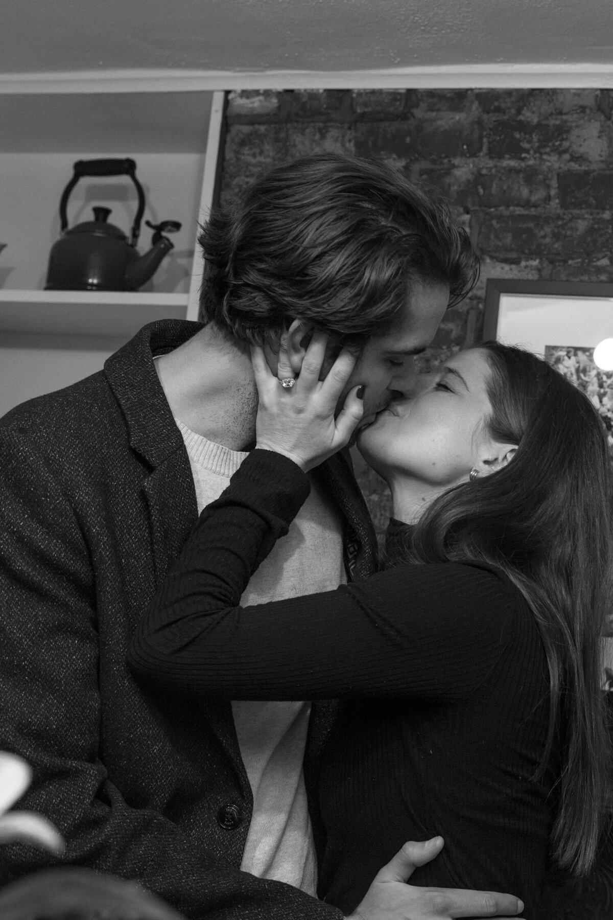 Young caucasion couple kissing near their mantle.