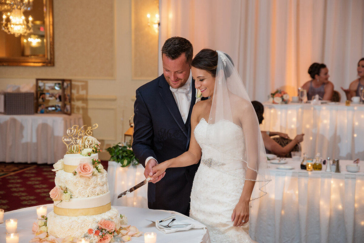 Wedding couple cutting cake during reception at Ambassador Banquet & Conference Center.