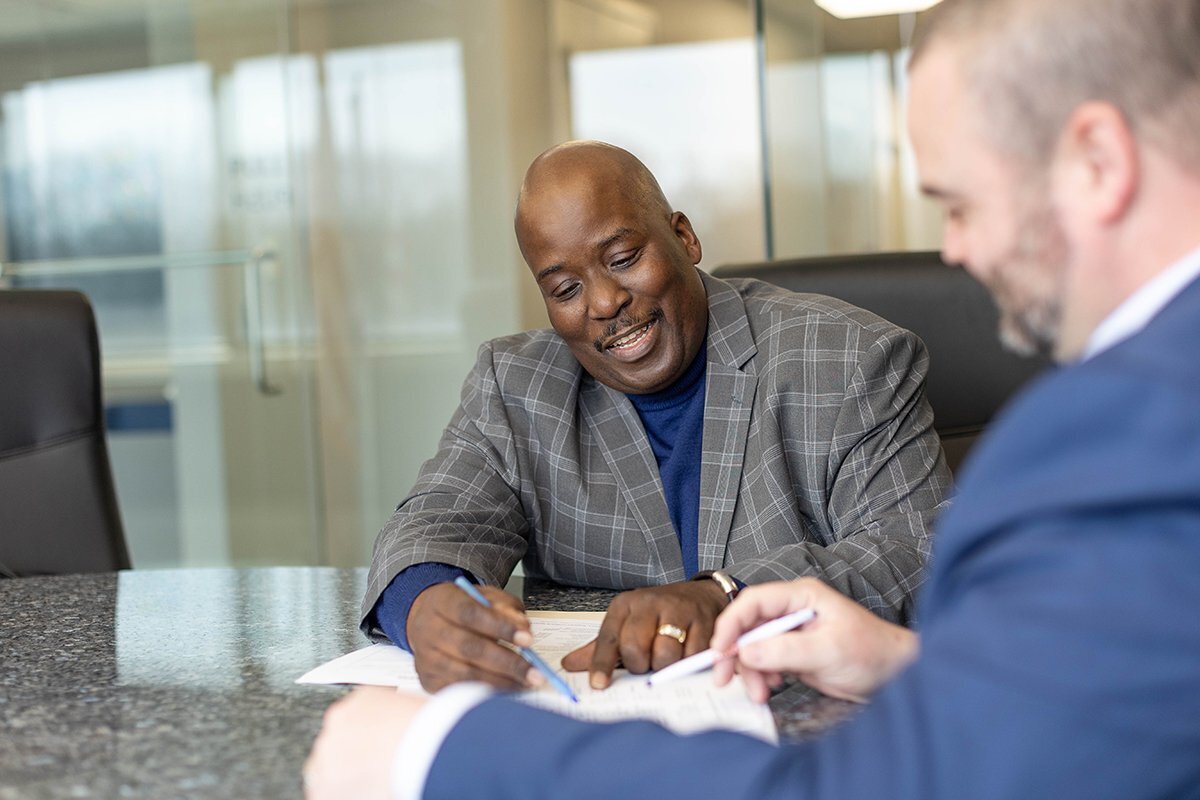 conference room with glass walls with an African-American businessman explaining documents to a customer
