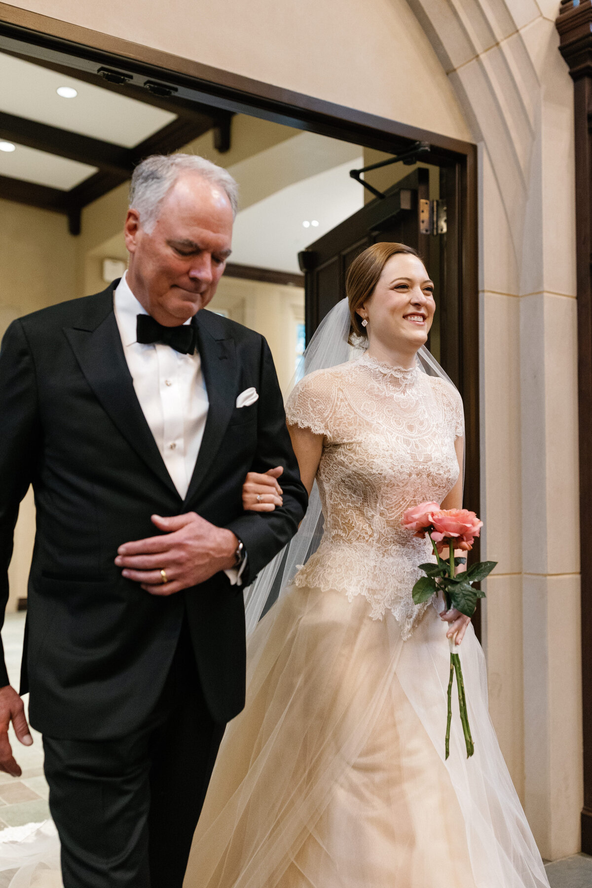 Bride walking down the aisle with her father, holding a peony bouquet