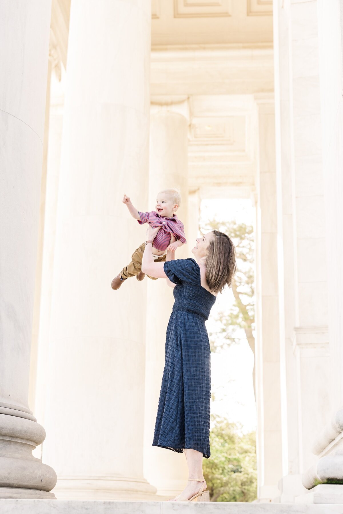 Mom holding her baby boy up in the air at the Jefferson Memorial