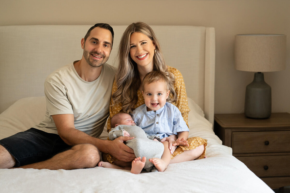 family posing for newborn photos on their bed