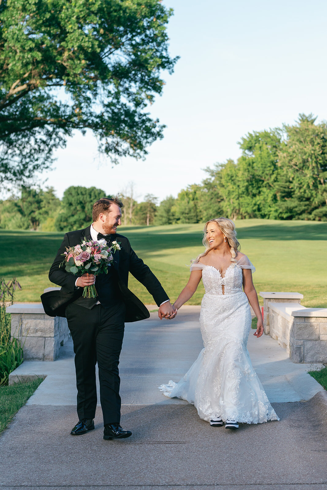 Bride and groom walking by the golf course at Wedding party pictures at Meadowbrook Country Club in St. Louis