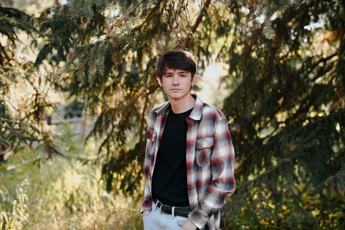 Male high school senior pictured among evergreen trees