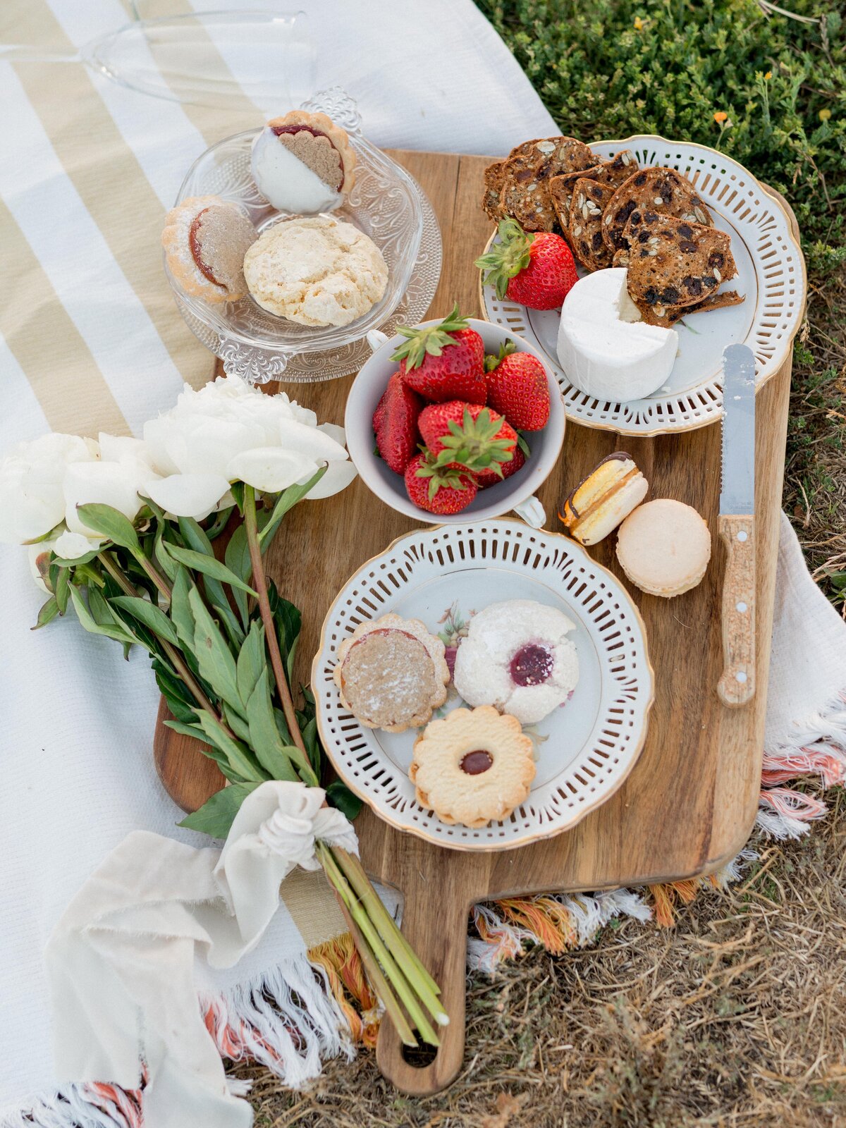 Elegant picnic spread with strawberries, cookies, and flowers