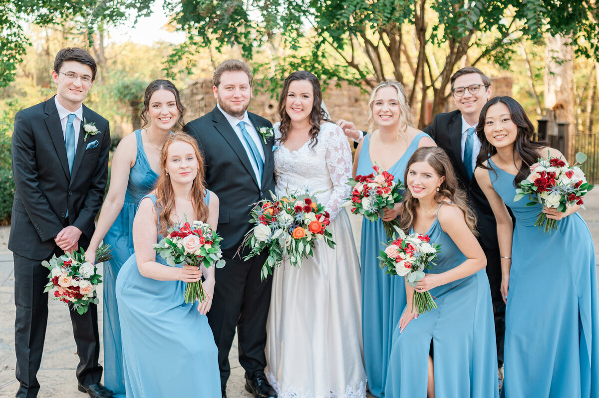 Newlyweds smiling with their wedding parties around them