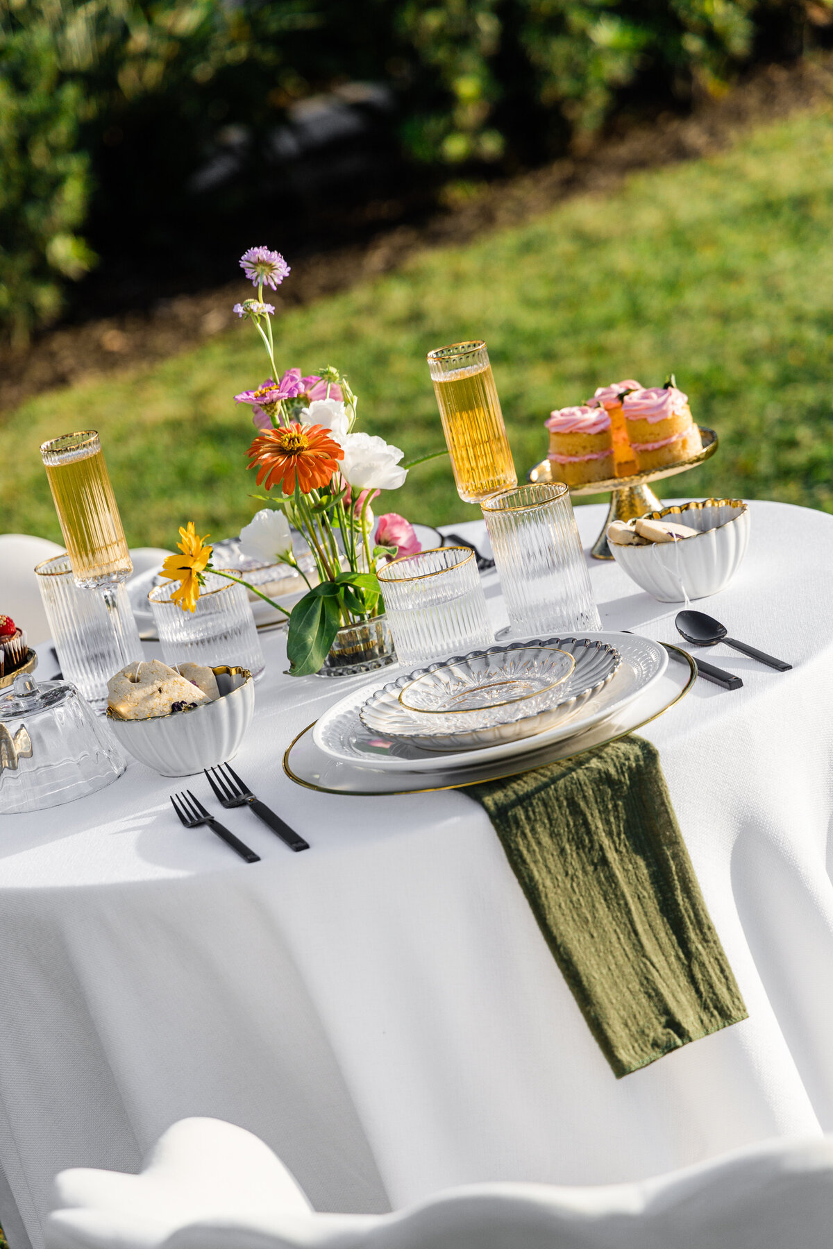 pink orange and white flowers on white table cloth with mixed metal place setting and mini chocolate cupcakes