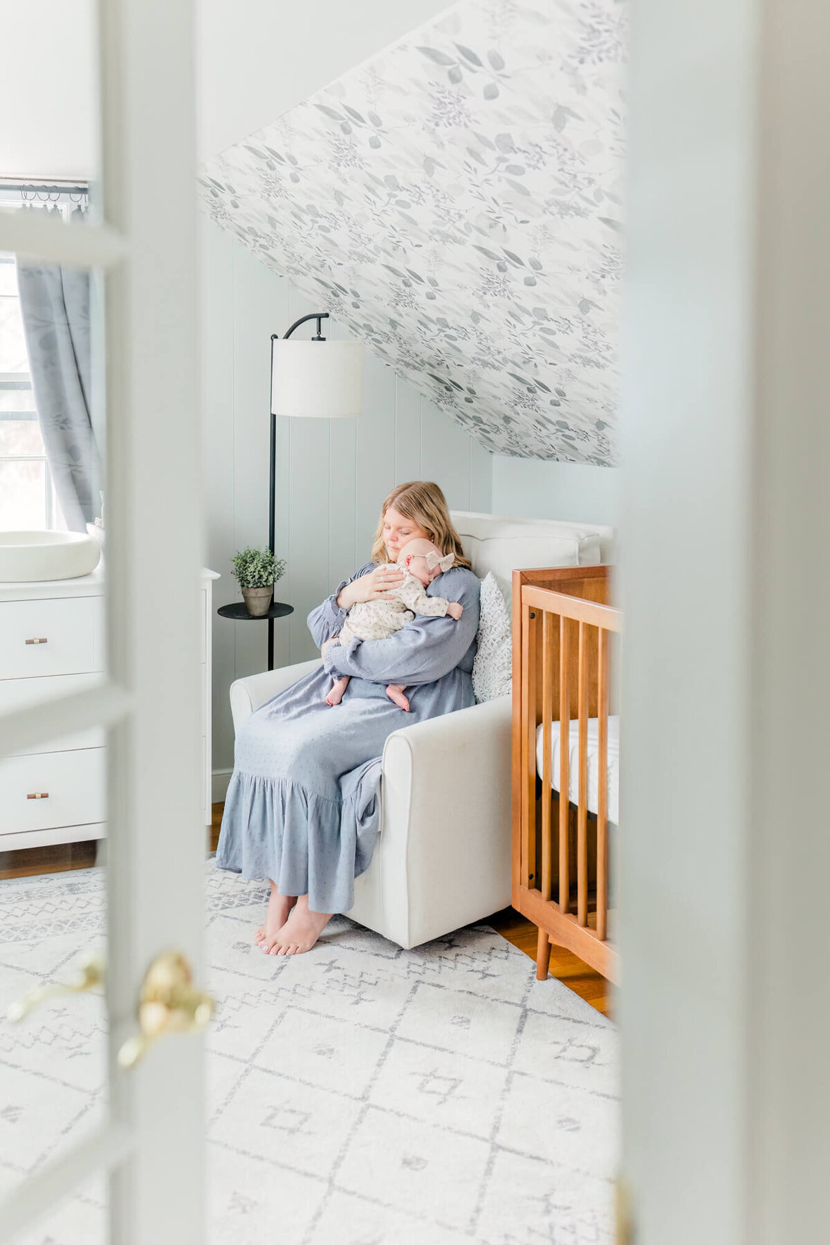 Mom rocks her baby to sleep in the nursery