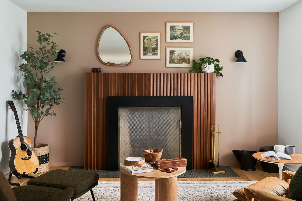 Indoor living room with blush walls, wood flooring and comfy seating surrounding a fireplace