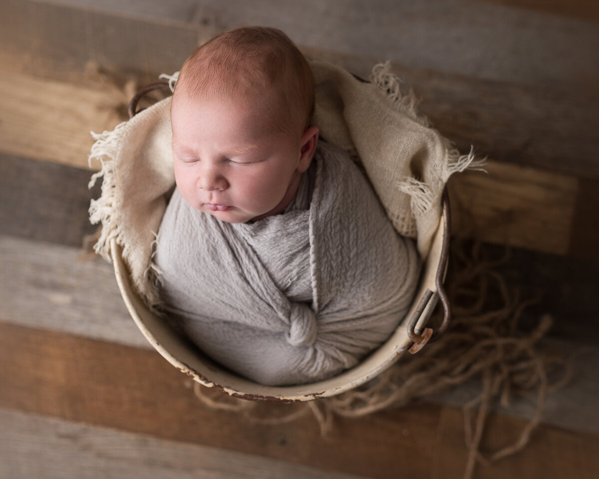 Wrapped newborn in a creative Bucket by Laura King