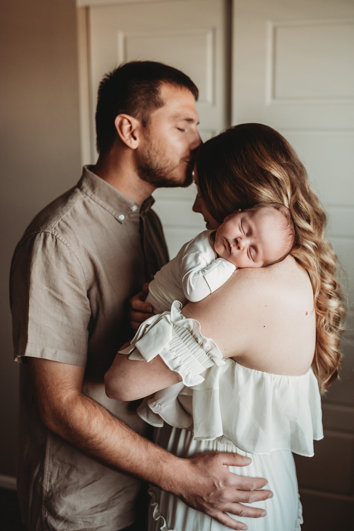 baby sleeping on mom's shoulder while dad kisses wife, by denver newborn photographer Photography by Alyssum