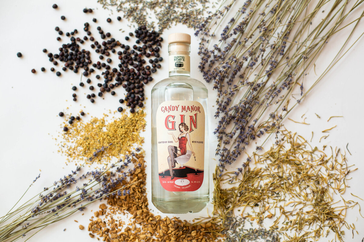 Boutique gin bottle shown surrounded with herbs that flavor gin