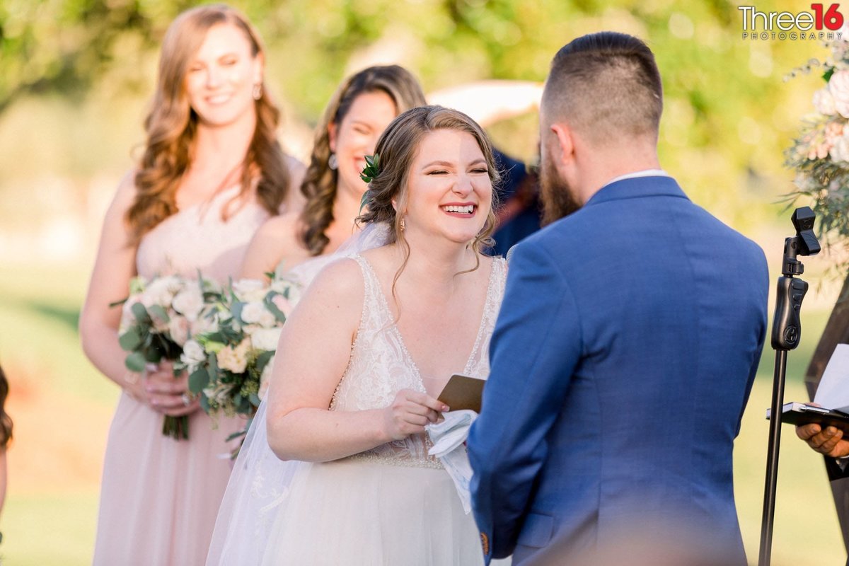 Bride laughs as she reads her vows to her Groom