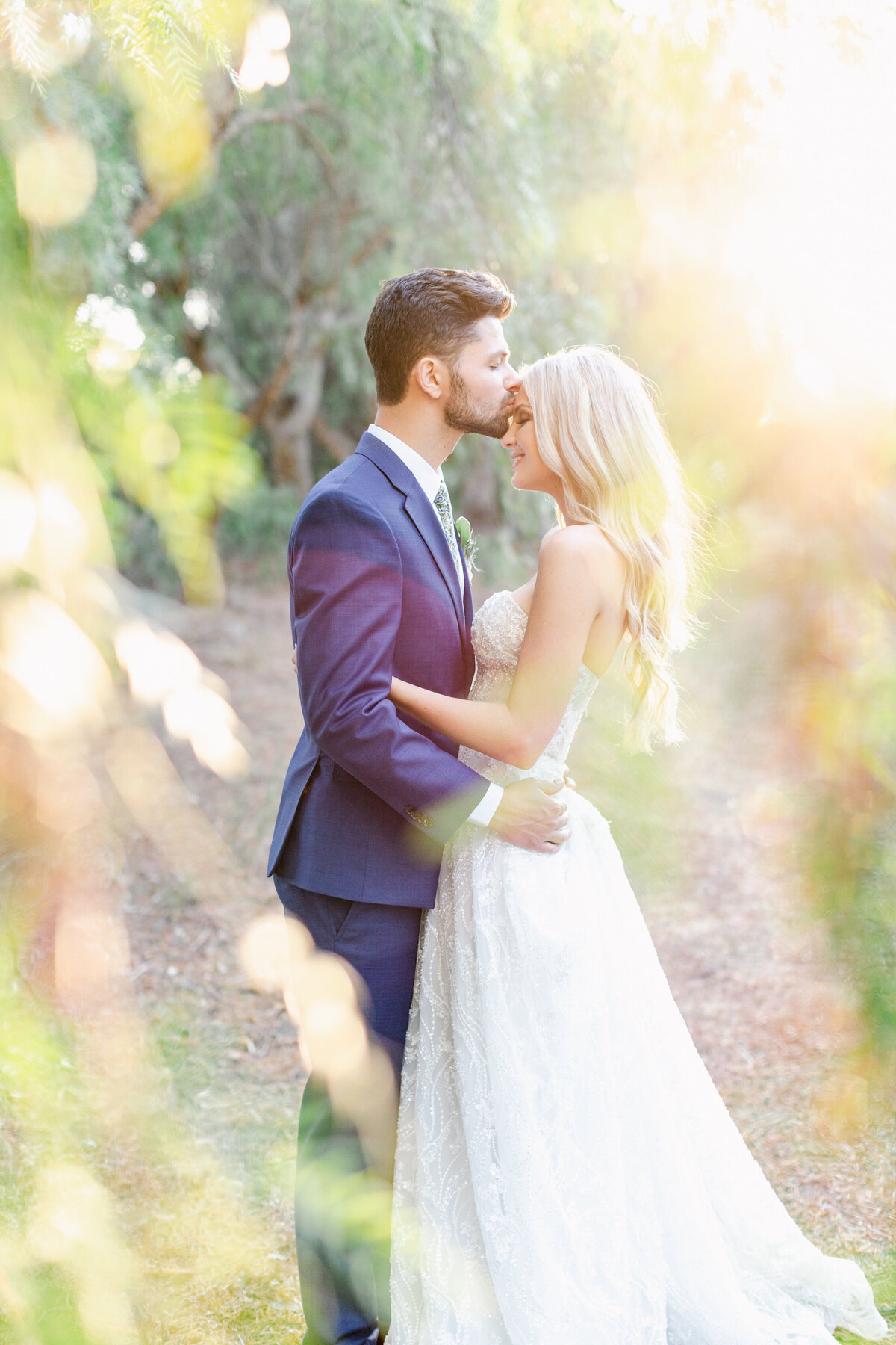 Peeking through the golden light hitting the greenery you see an image of the bride and groom.