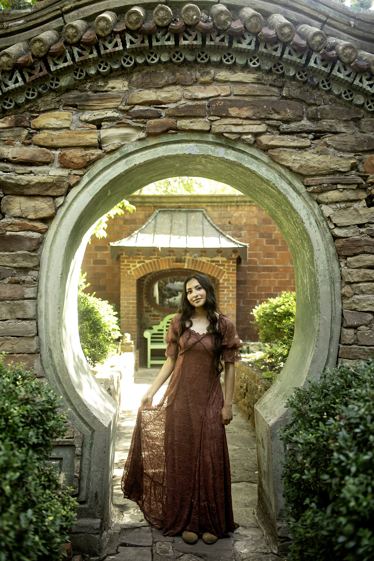 Captured in a peaceful moment, a high school senior poses amidst the rich greenery and colorful flowers of Chandor Gardens, Weatherford, TX, celebrating her journey