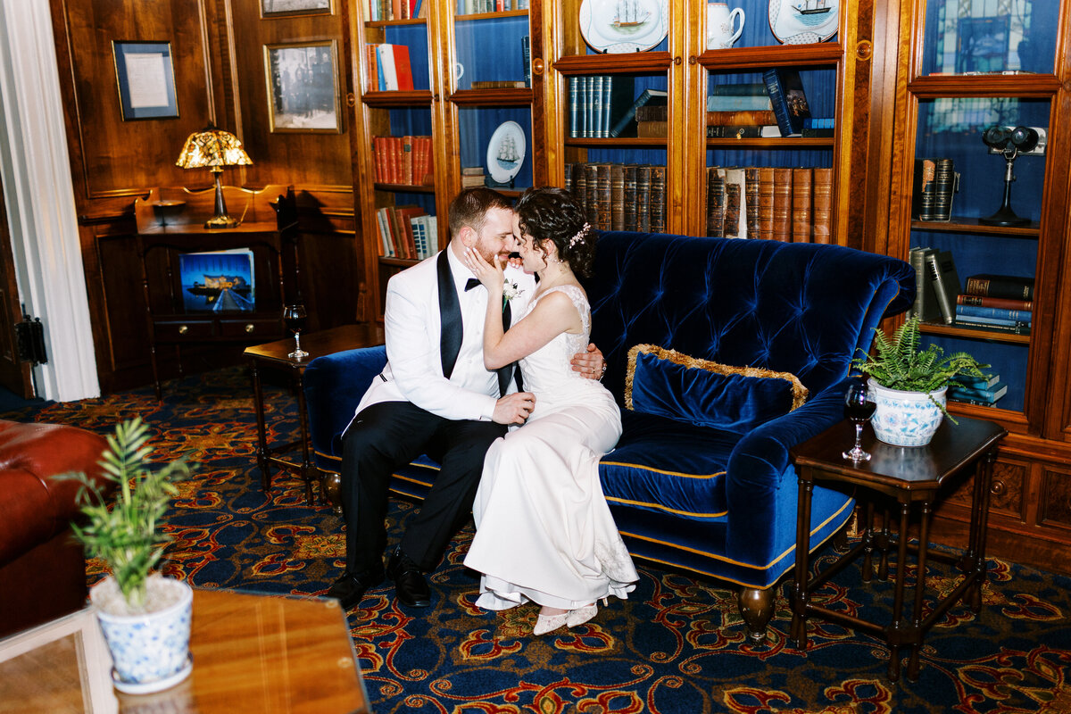 bride and groom sitting on the sofa kissing at St, James hotel