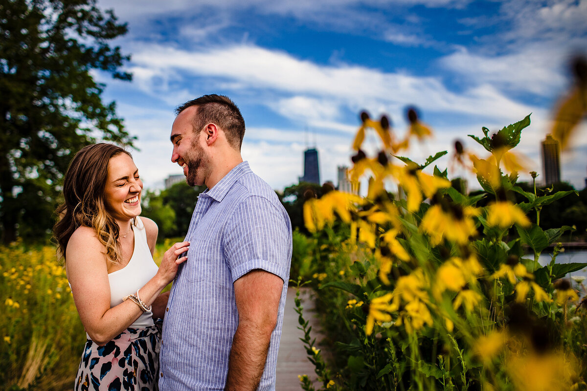 A couple laughs in a row of sunflowers during a Lincoln Park engagement session.