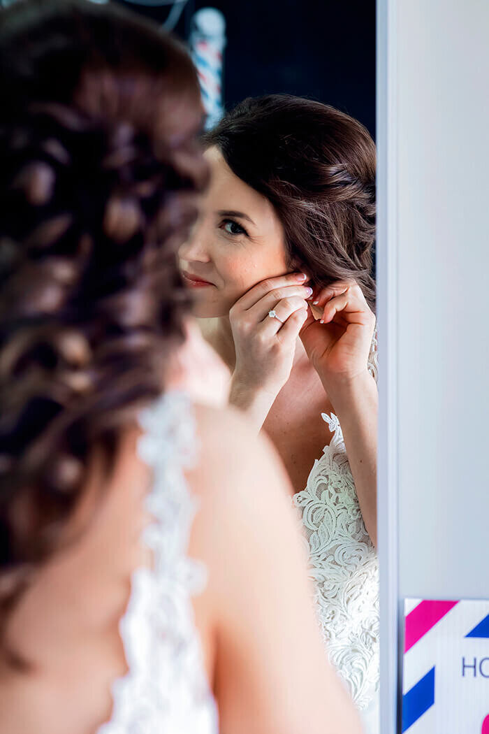 bride-puts-on-earrings-mirror