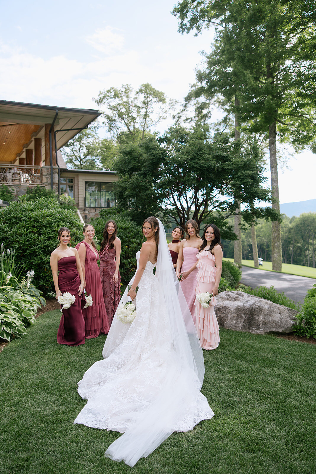 Bride standing with bridesmaids in floral gowns during outdoor portraits at Trillium Links & Golf Club in Cashiers, NC.