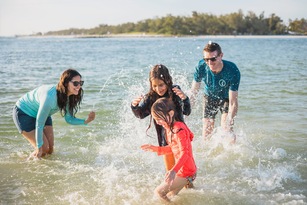Family plays in water while wearing clothing for outdoor lifestyle brand in Southwest Florida