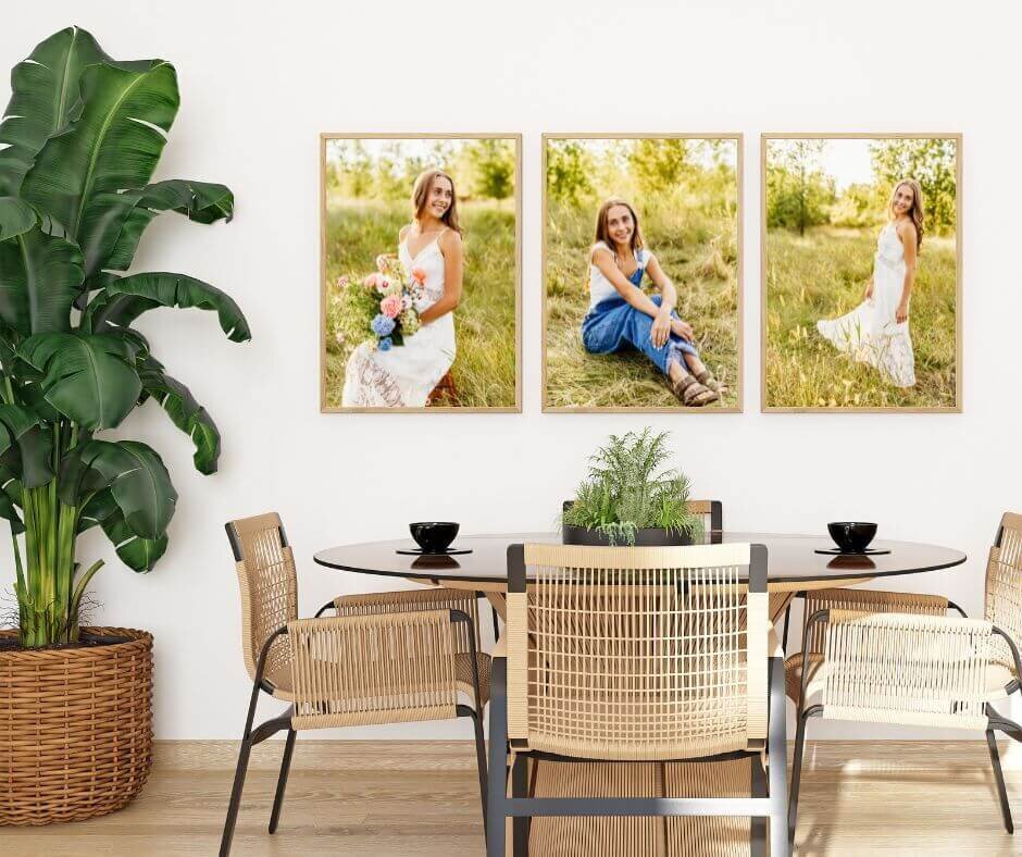 three gorgeous high school senior portraits hanging next to each other on a white dining room wall with a natural colored wood table and chairs in front of them