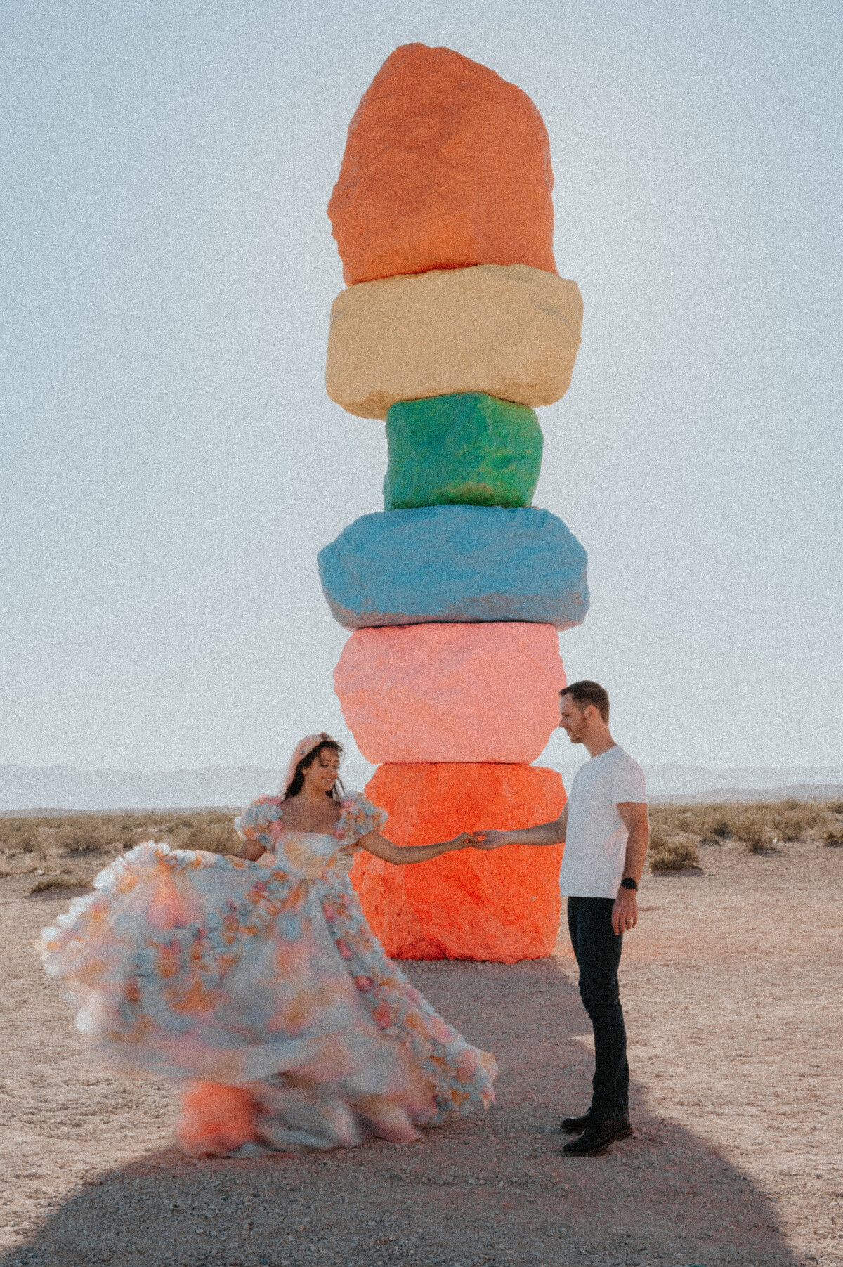 a couple poses at the seven magic mountains with their elopement photographer