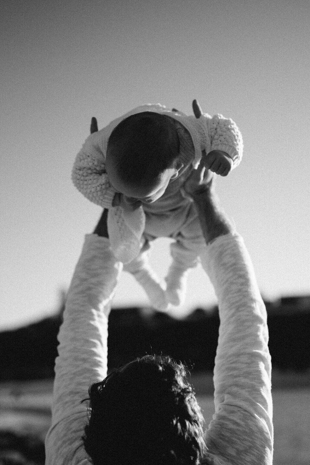 Dad lifting his baby in the air a on a Sydney beach – candid lifestyle family photography.