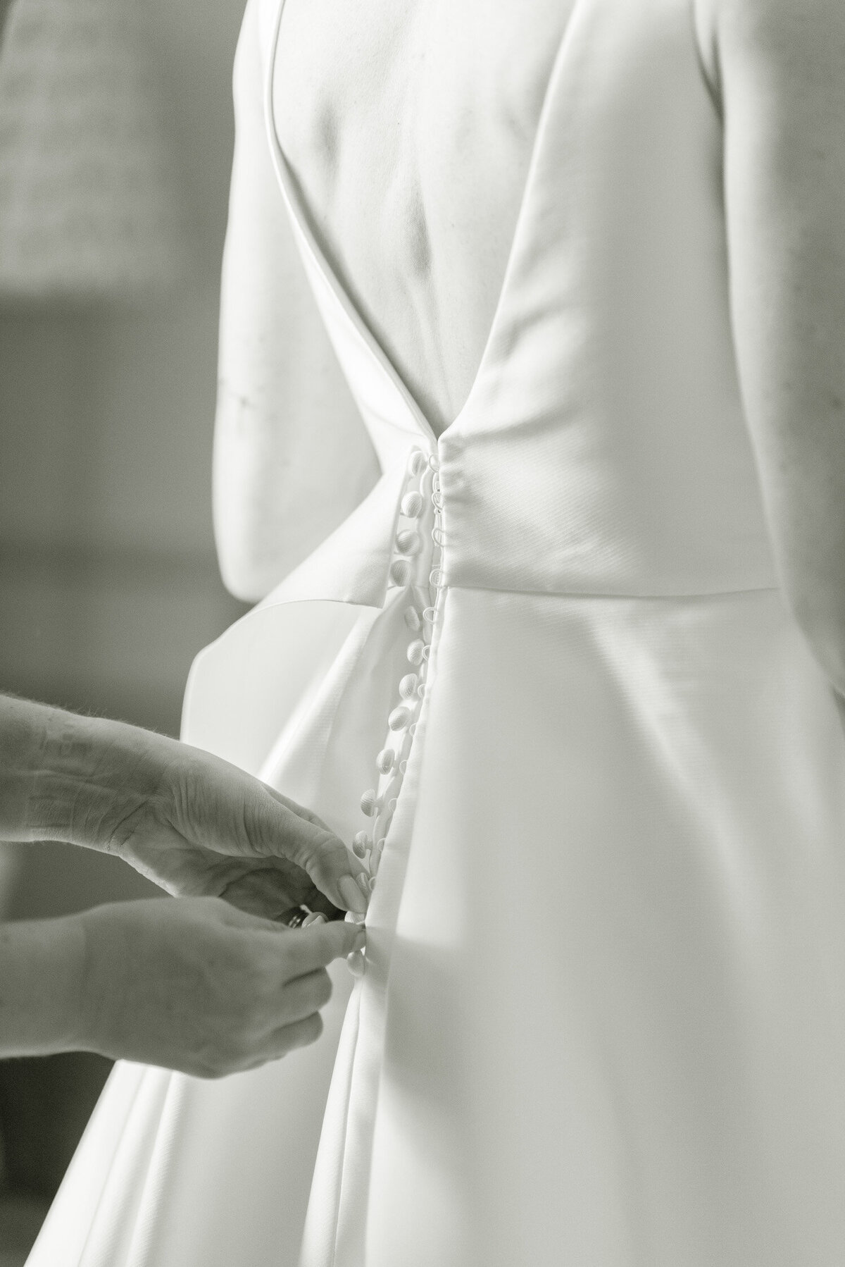 Detail image of a Jesus Peiro wedding dress being buttoned at the back on a Gleneagles wedding day.