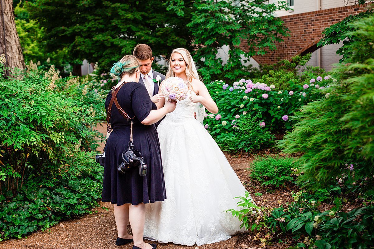 Mahlia assisting bride with dress and bouquet in the outdoor courtyard at Gaylord Opryland