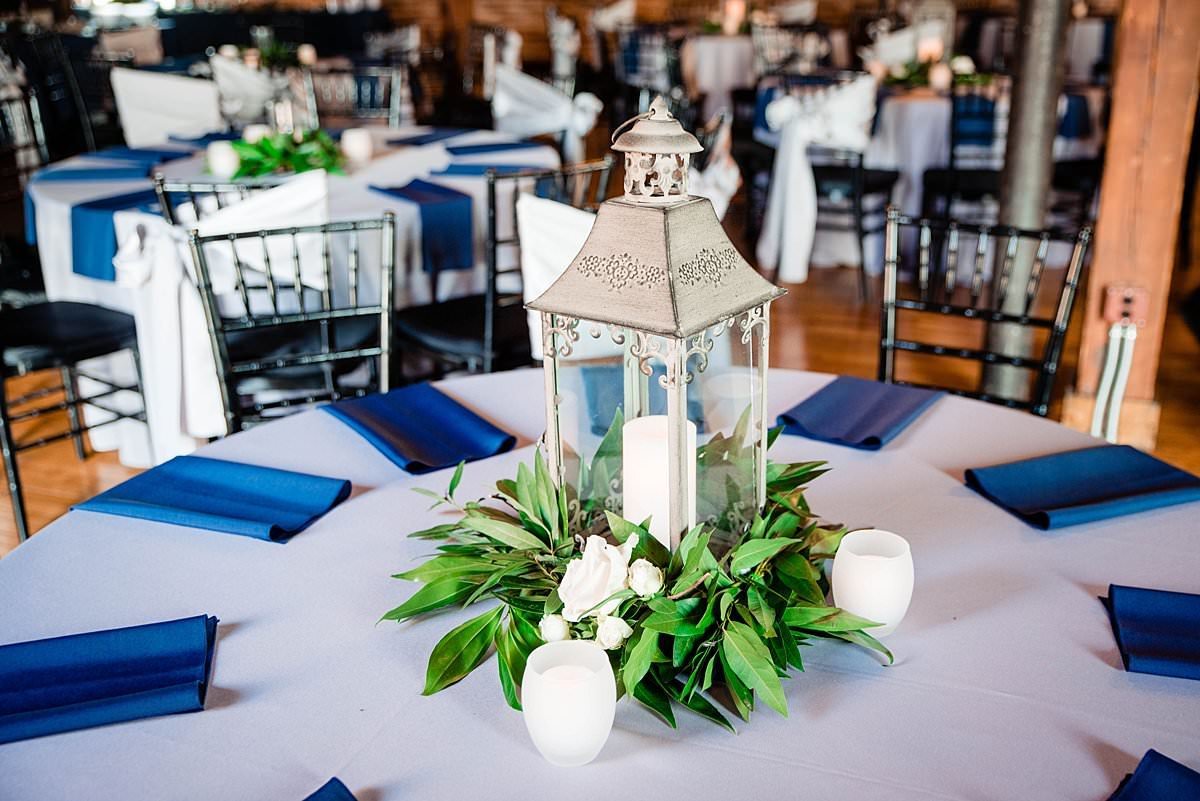 Tall silver lanterns as reception centerpieces on round tables with Magnolia leaves around the base