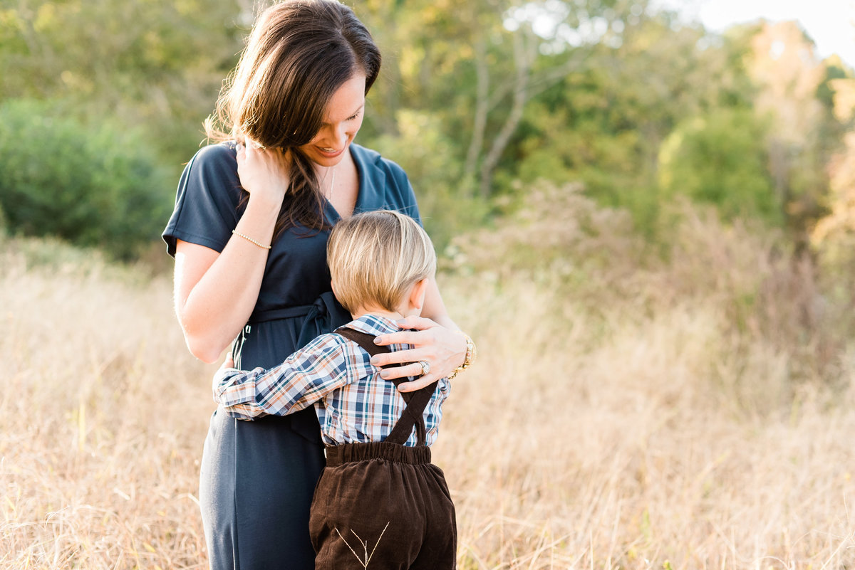 Toddler boy hugs his mom in a field during their family photography session in Raleigh NC. Photographed by Raleigh NC Family Photographer A.J. Dunlap Photography.