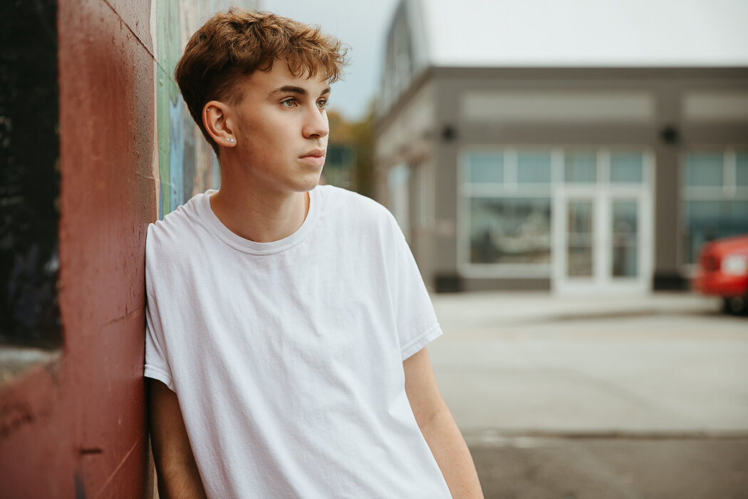 Senior boy leaning on a graffiti wall in Olympia WA