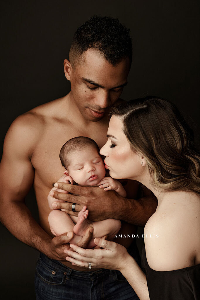 Dark luxury portrait of family with newborn baby