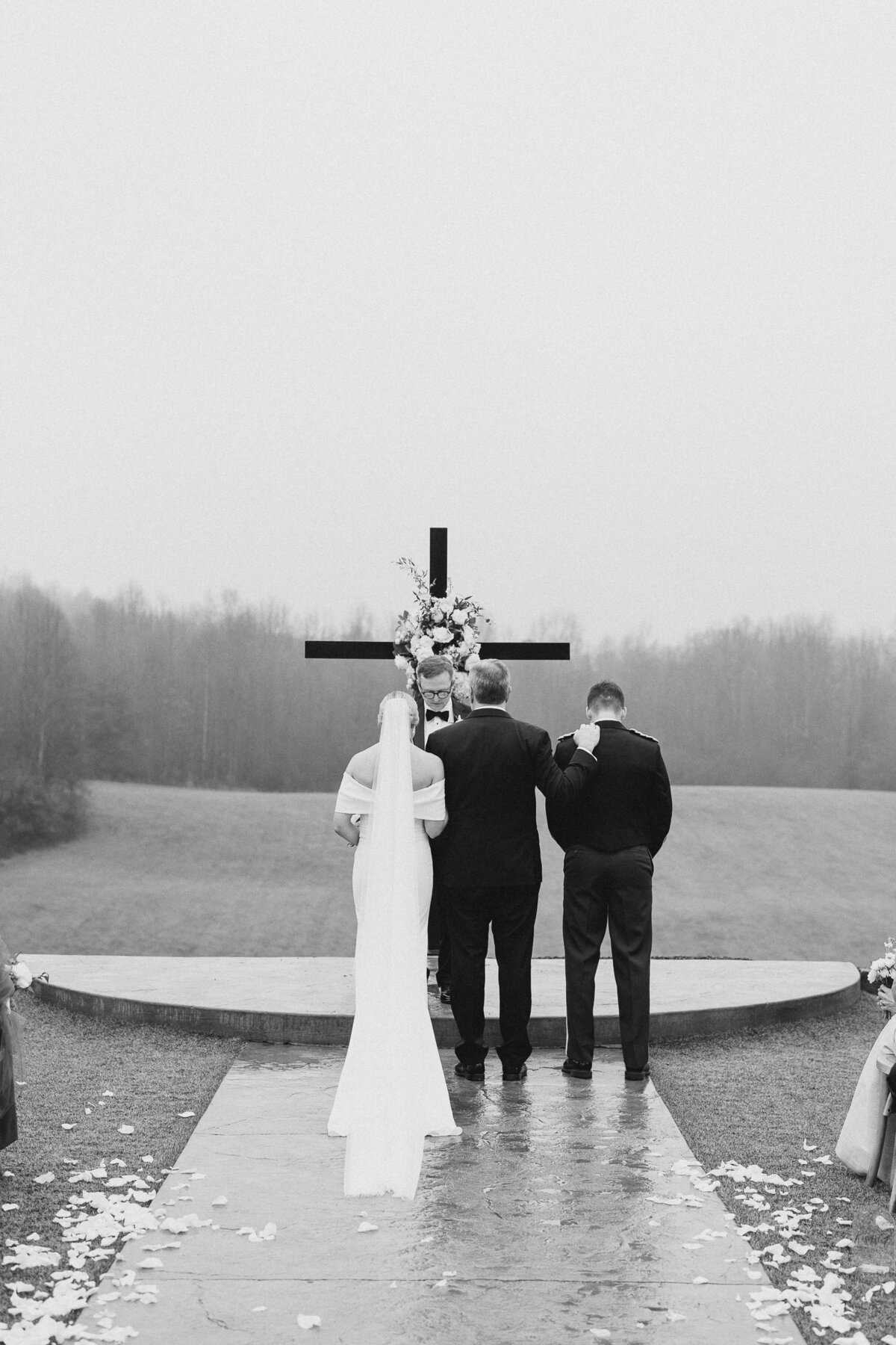 Bride and groom standing in front of a cross