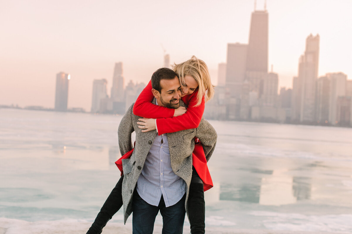 An engagement photo in front of a frozen Lake Michigan with the Chicago skyline in the background.