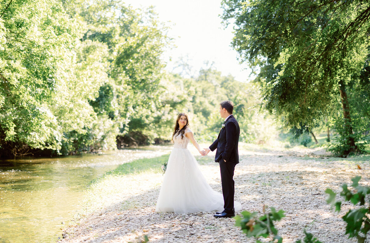bride and groom stands  by the river
