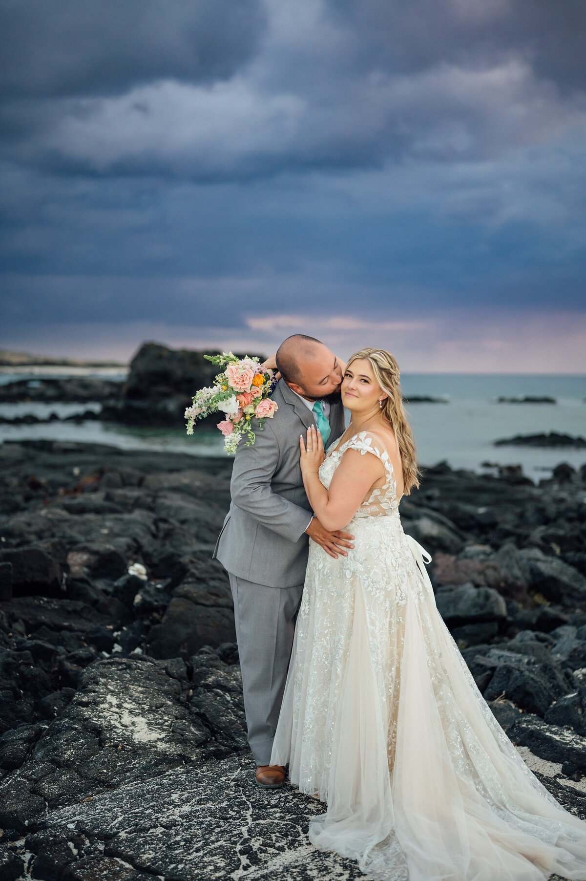groom kisses bride on cheek during their wedding day on the beach
