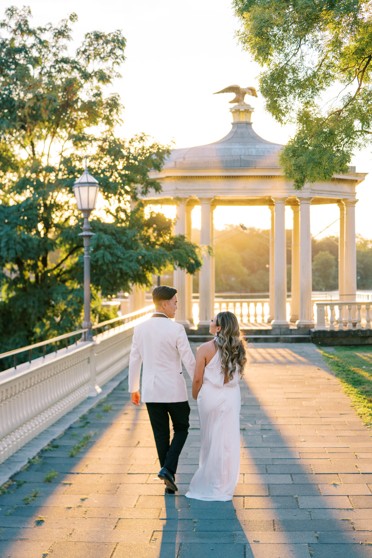 Bride and groom hold hands as they walk towards the sunset at Water Works by Cescaphe in Philadelphia.