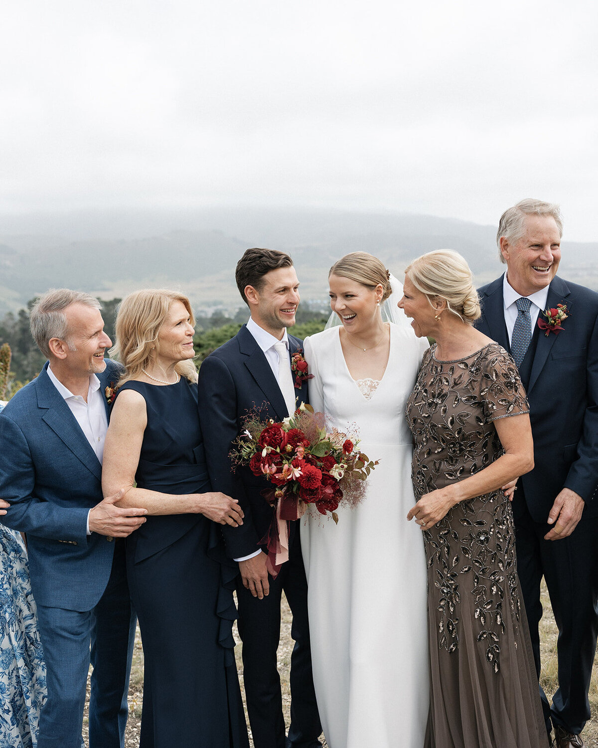 Bride and groom laughing with family during a wedding portrait