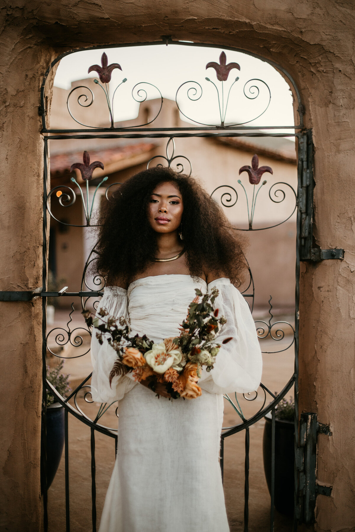Bride holding bouquet in front of a southwest courtyard entrance
