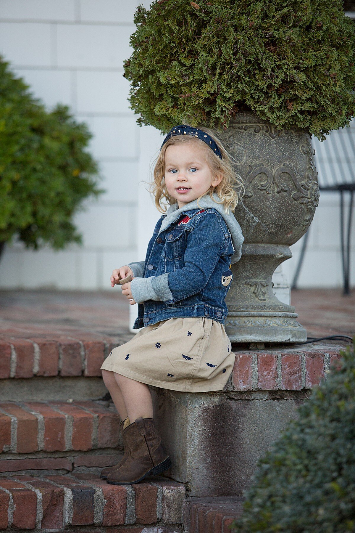 Trendy toddler girl sitting on brick steps