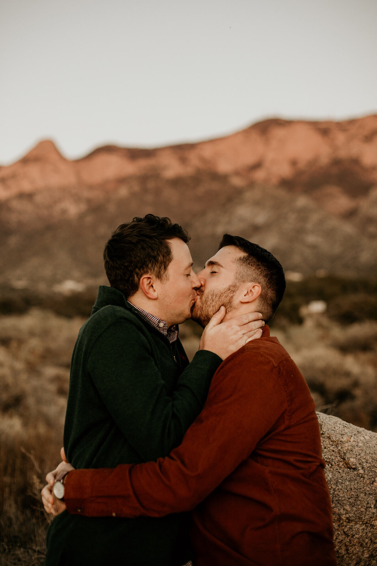 two men hugging and kissing in the desert