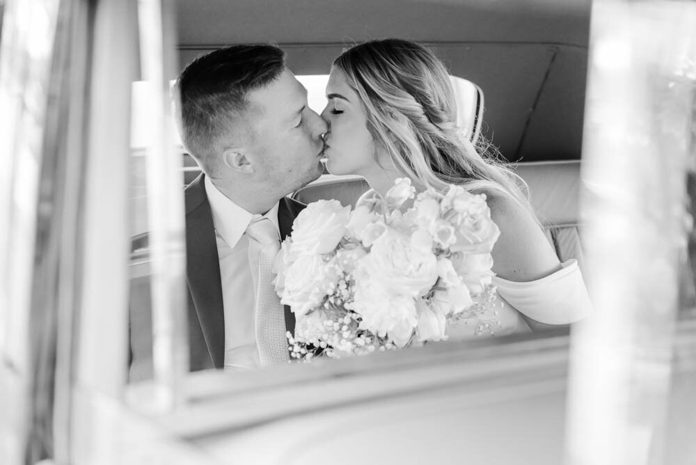 Bride-and-groom-kissing-in-backseat