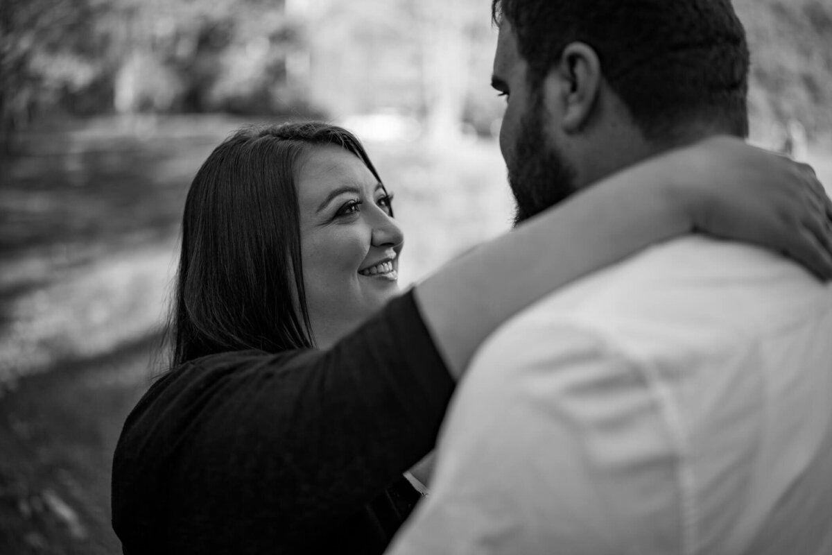 Black and white engagement photography of a couple holding each other and smiling at brush creek park, beaver county, PA