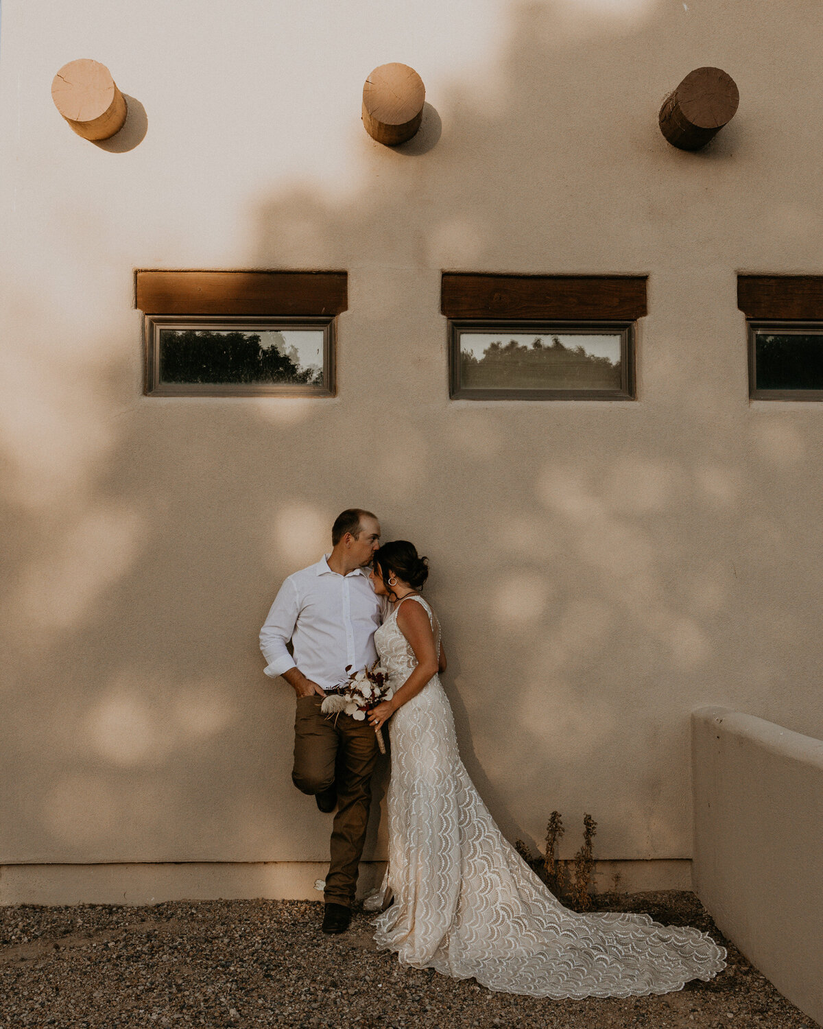 newlyweds standing against an adobe  style casita