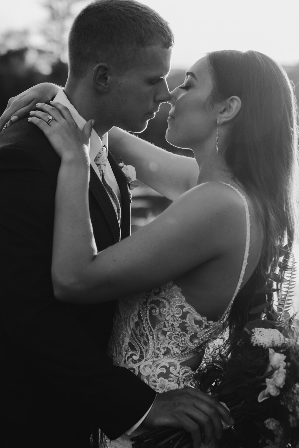 black and white photo of a wedding couple as they lean in for a kiss