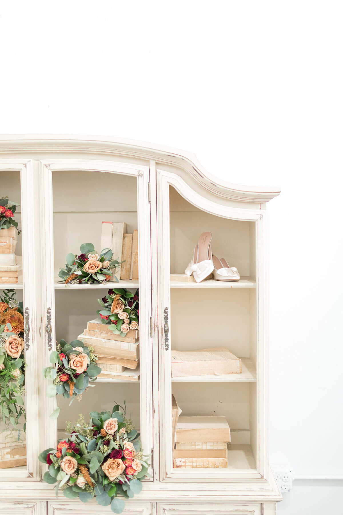 RUST AND SAGE GREEN WEDDING FLORALS INTERMINGLED WITH VINTAGE BOOKS, AND SATIN HIGH  HEELS