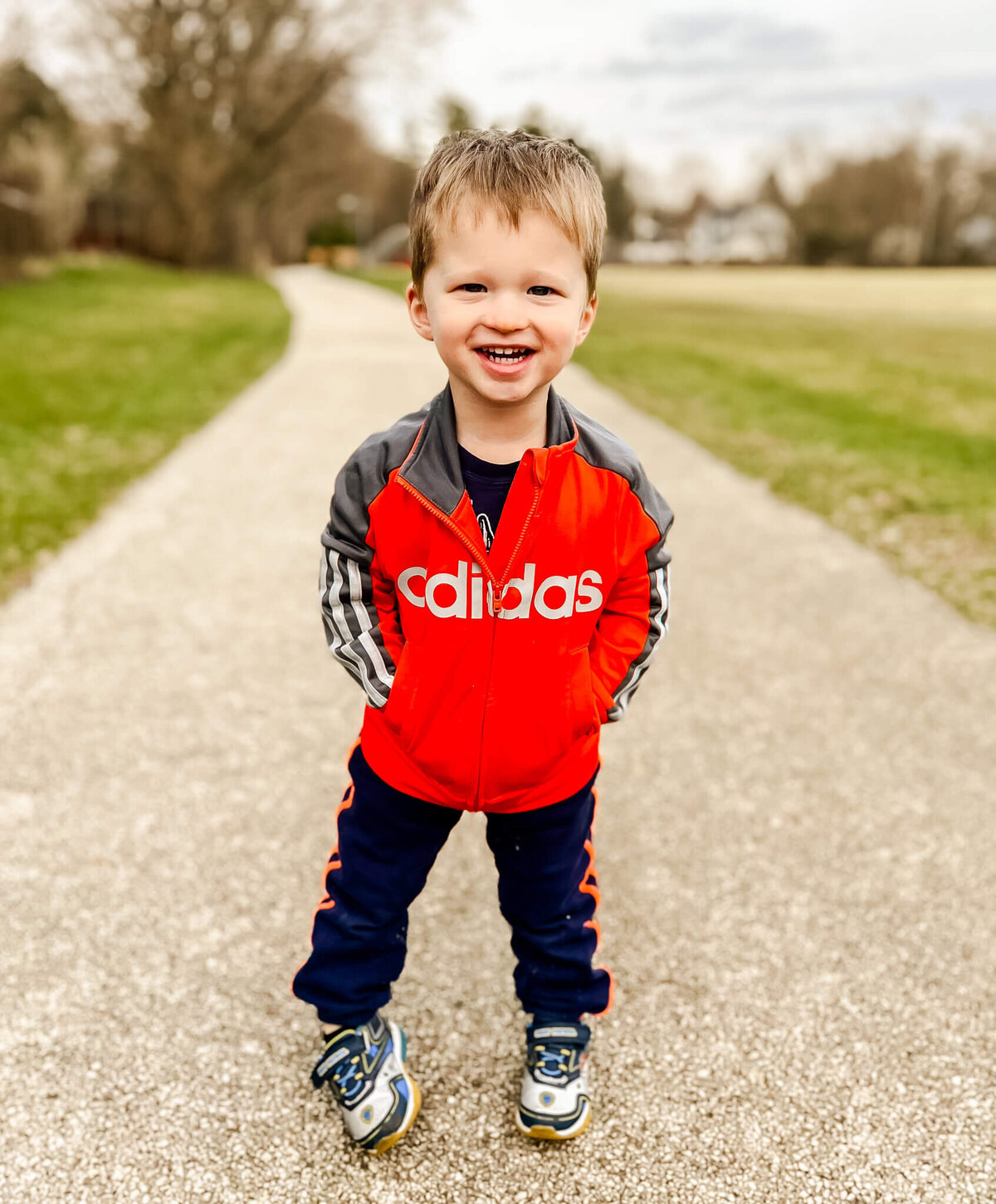 Toddler walking on path with hands in his pocket near Naperville, IL.