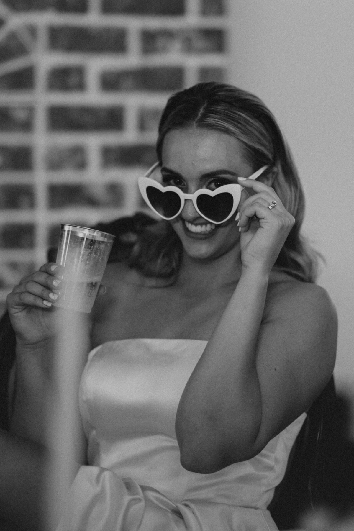 A woman peers through her heart shaped sunglasses